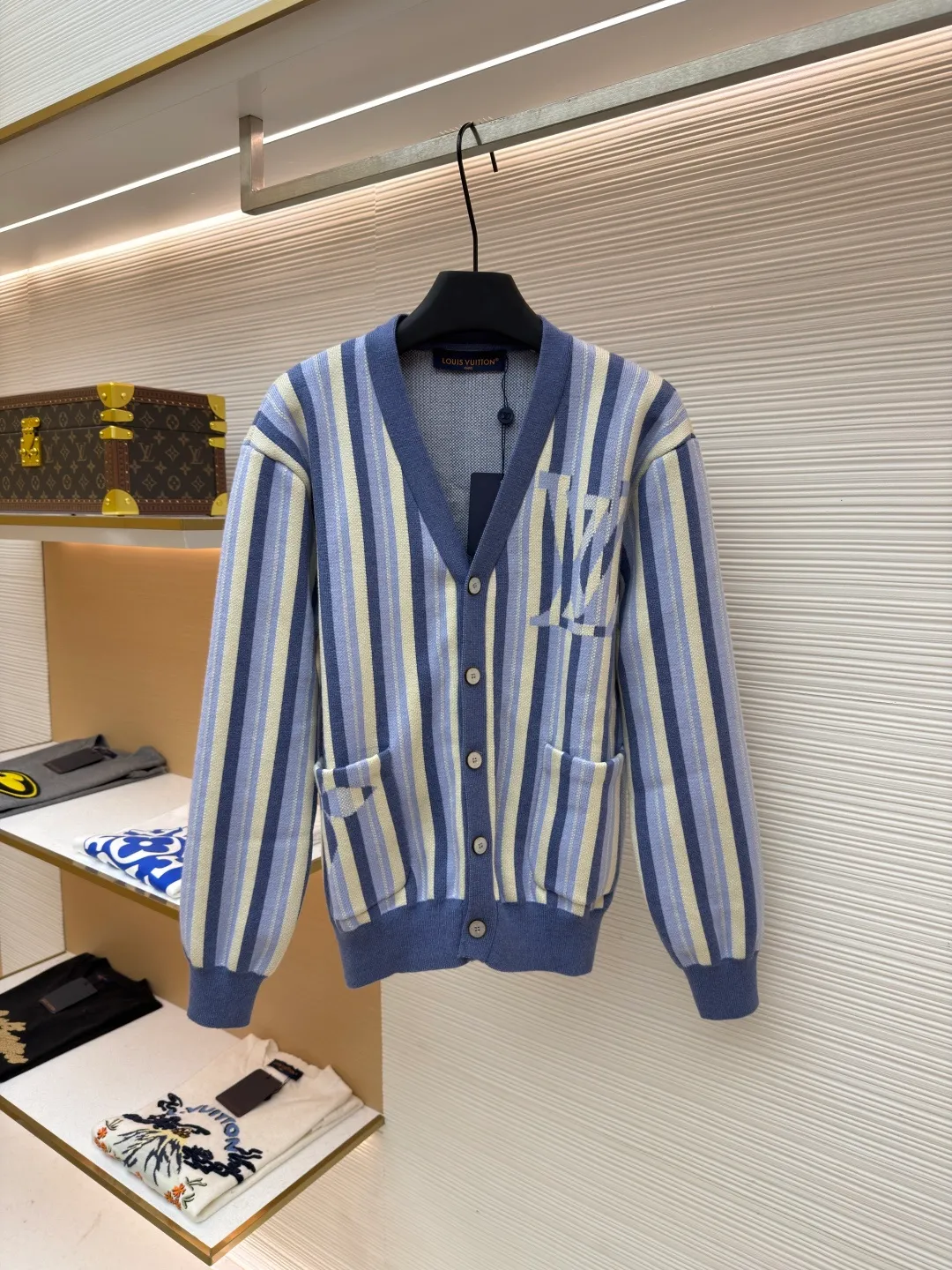 LOUIS VUITTON striped jacquard single-breasted sweater ●Original version: Purchased and developed for 15100 ●Item number: 1682314-C00 ●Fabric: wool fabric ●Technology: jacquard knitting ●Color: blue ●Version: fitted version ●Weight: about 930 grams ●Size: S-M-L-XL ●Description: This LV striped knitted cardigan is made of high-count worsted wool blended yarn. The double-ply threading process enhances the yarn's toughness. It is not easy to pill and has an outstanding drape feeling. The body of the garment adopts vertical jacquard weaving technology, with navy blue, light blue and off-white yarns interlaced with each other. The stripe width and spacing are precisely controlled by a computerized flat knitting machine, so that the color transition is natural and even. The LV letter jacquard on the left body has been debugged several times through plate making to ensure that the pattern is three-dimensional and clear. The V-neck, cuffs, and hem all use ribbing technology and are pre-shrunk to shape, making them less likely to loosen and deform after long-term wear. The buttons are made of custom-made metal, with matte sandblasting on the surface, and are hand-stitched with the seams of the body. The pockets use welting technology, and the edges are flat without jumpers. Every detail reflects the exquisite clothing craftsmanship and brand ingenuity. The overall wiring is straight and delicate, the fabric is comfortable and soft, and the color is consistent without color difference. It can be matched with the same style to create a fashionable look and control various occasions. Customized accessories, complete with three standards, same style for men and women!